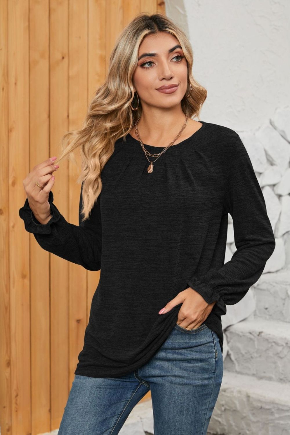 Black knit top with pleated yoke and ruffled cuffs, crew neck, long sleeves.