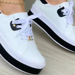White lace-up platform sneakers with black accents and gold buckle detail.