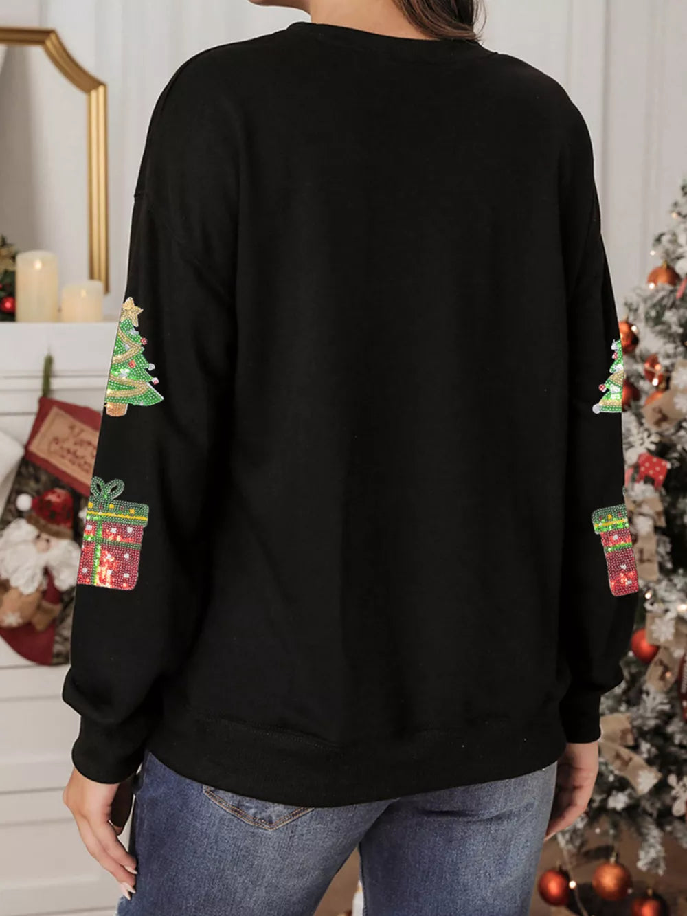 Black crew neck sweatshirt with sequin Christmas tree and gift embellishments on sleeves.