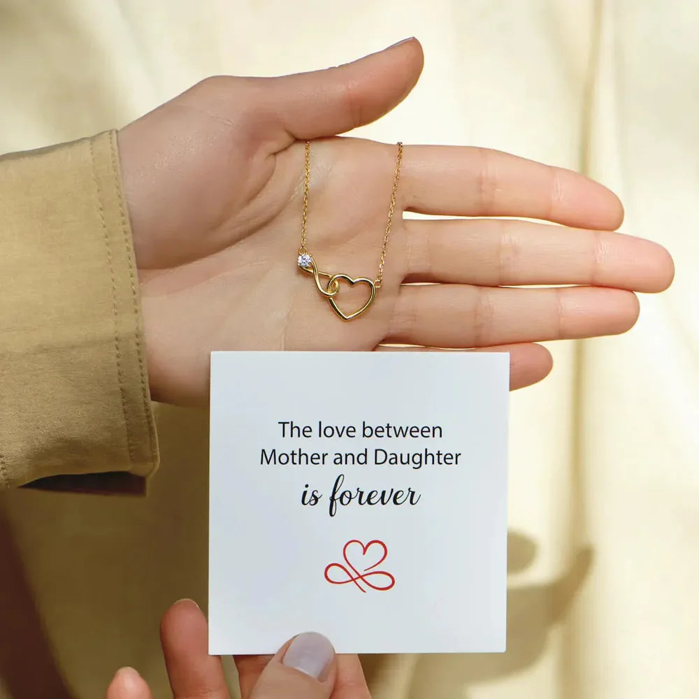 Gold necklace with intertwined heart and infinity pendant with a single clear stone.