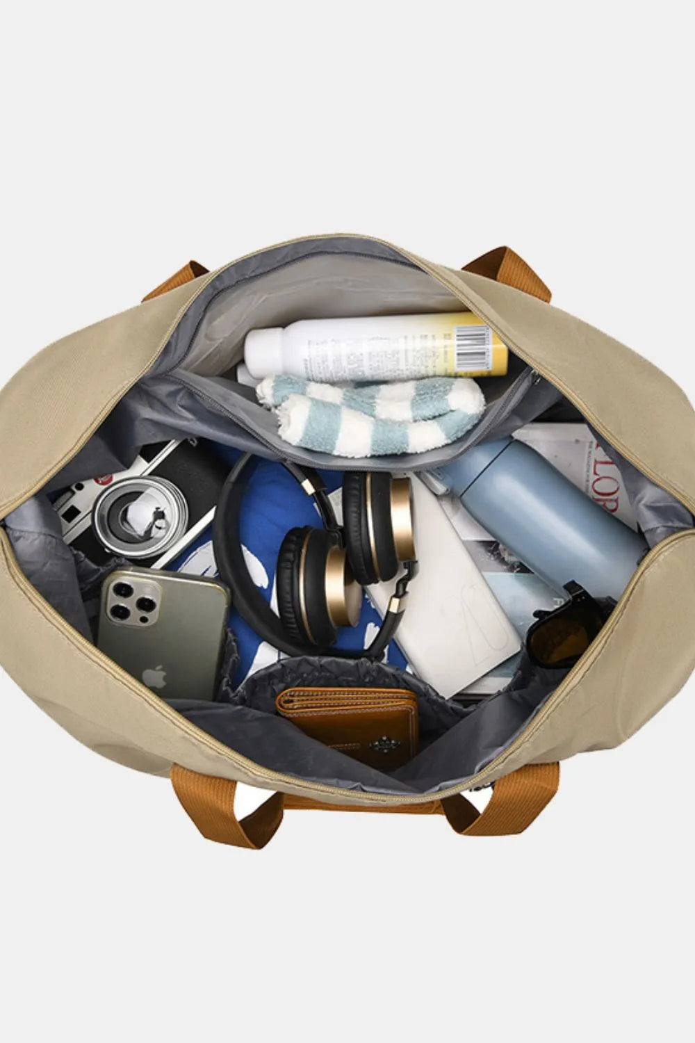 Loomirke Weekend Holdall duffel bag in tan, packed with essentials like headphones, phone, and toiletries.