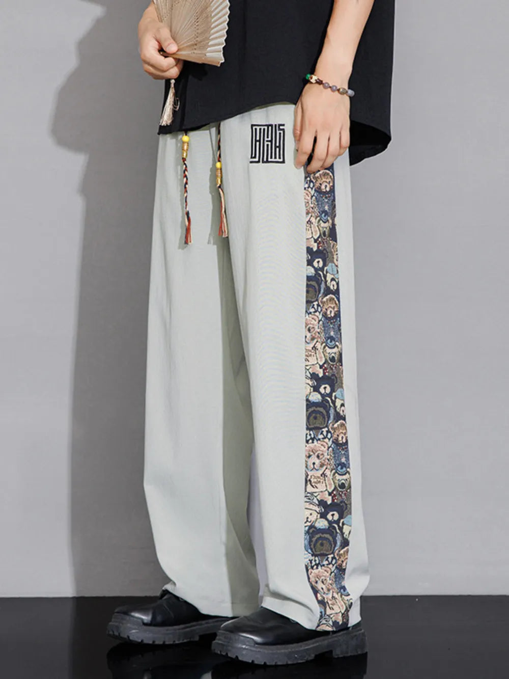 Men's light gray sweatpants with printed side stripe and drawstring.