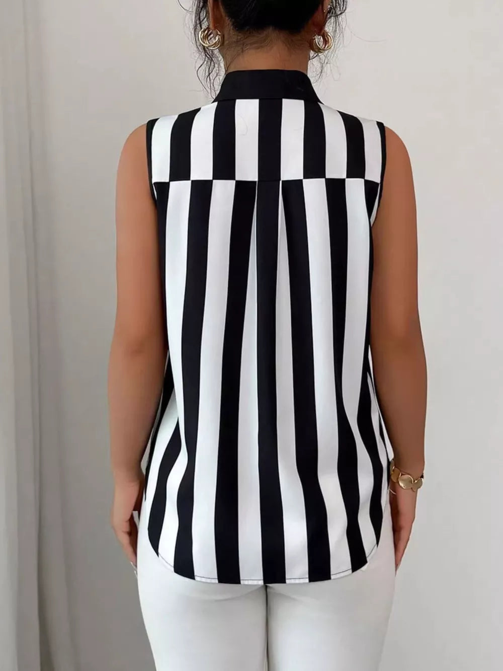 Sleeveless collared shirt in black and white stripes with button detail.