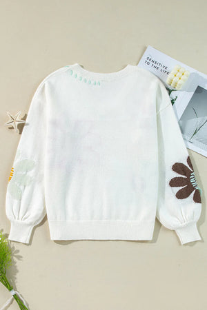 White knit sweater with embroidered floral and leaf details on sleeves and neckline.