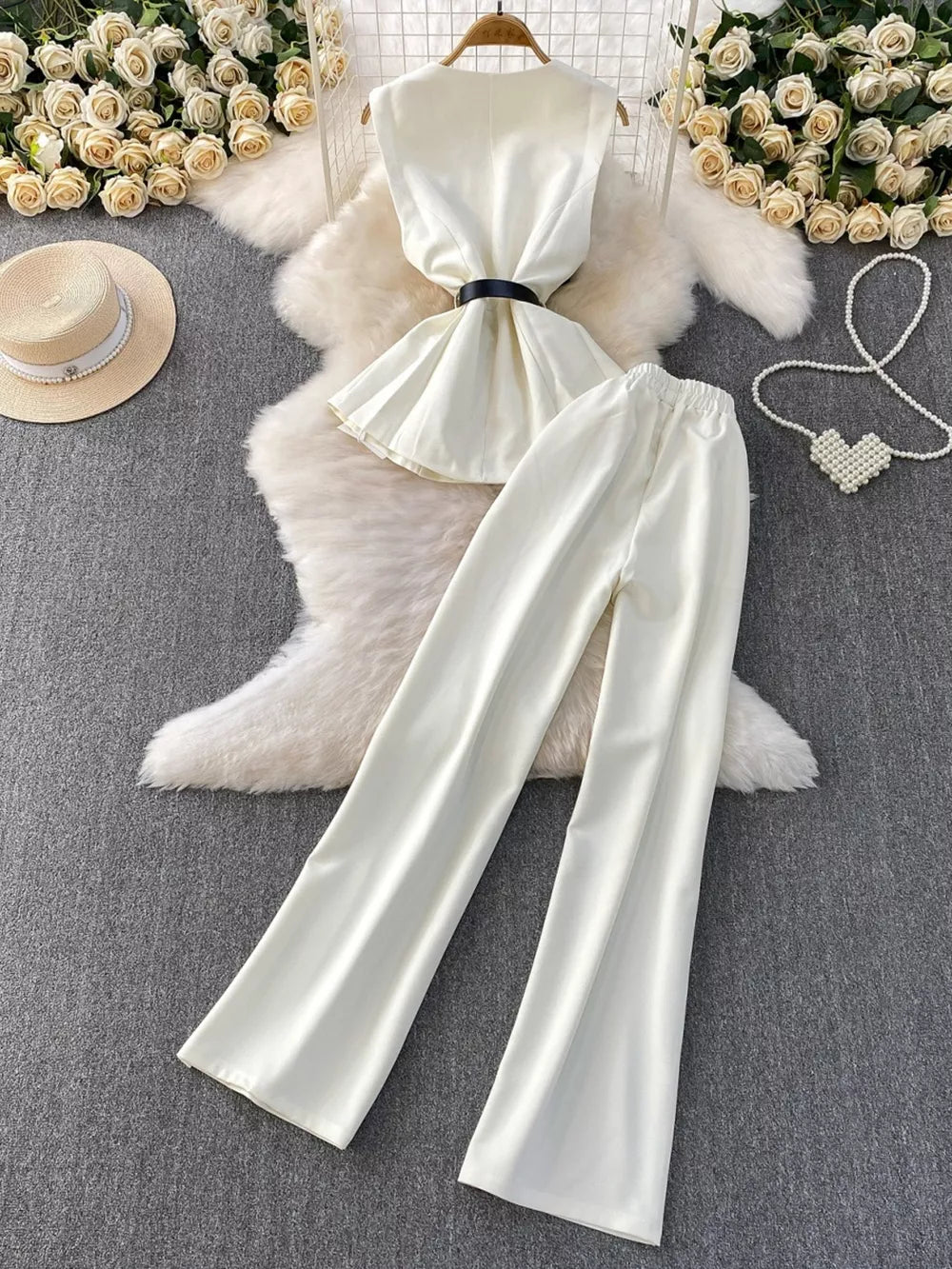 White belted two-piece set with wide leg pants and sleeveless top with pockets.