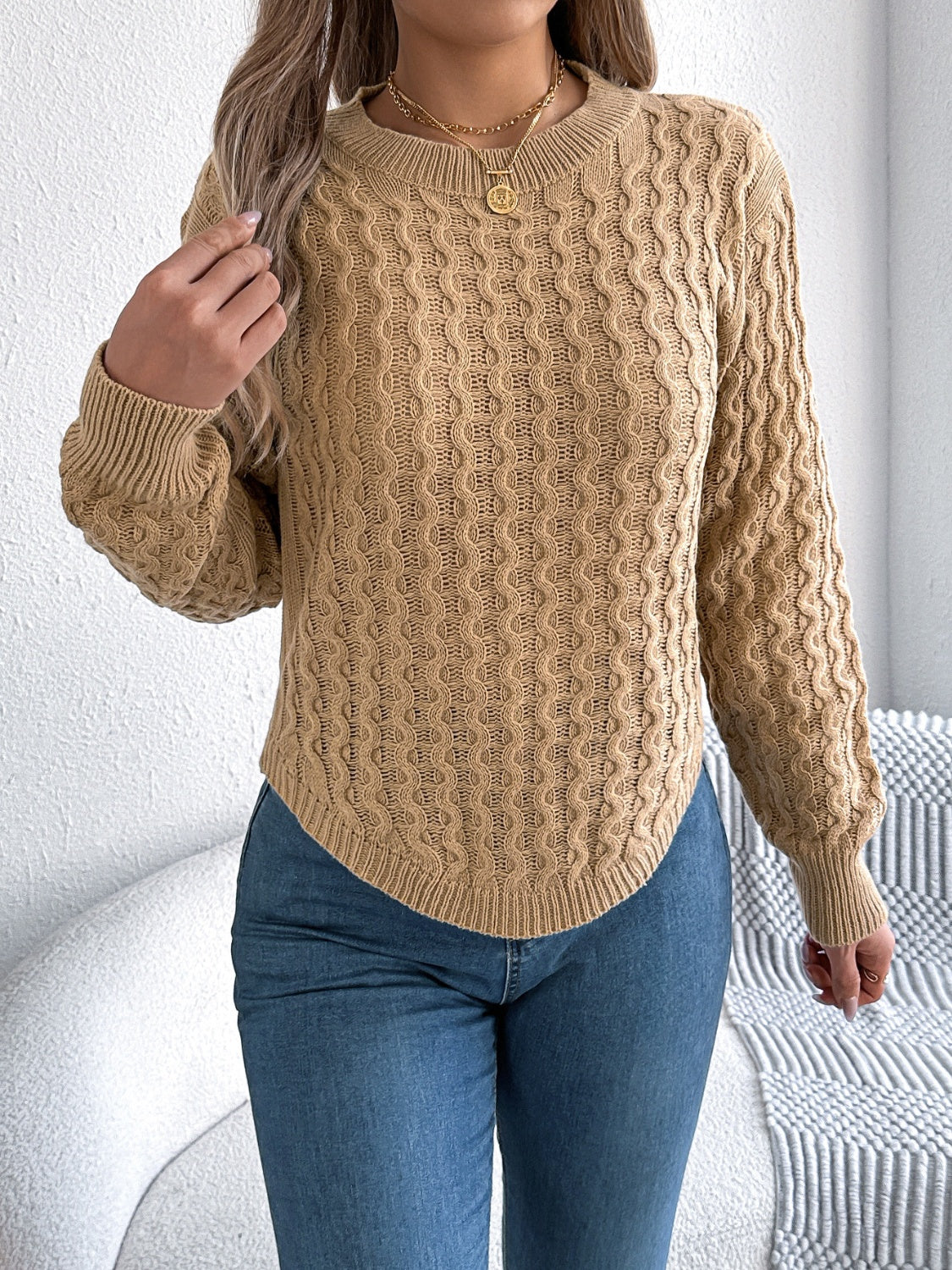 Camel knit sweater with textured cable pattern and asymmetric hem.