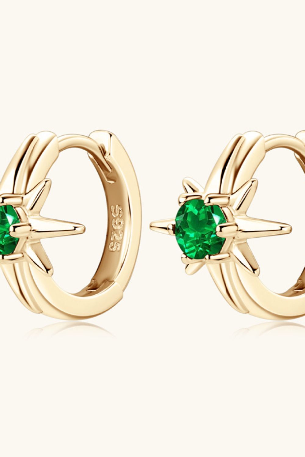 Gold hoop earrings with starburst design and emerald green stones