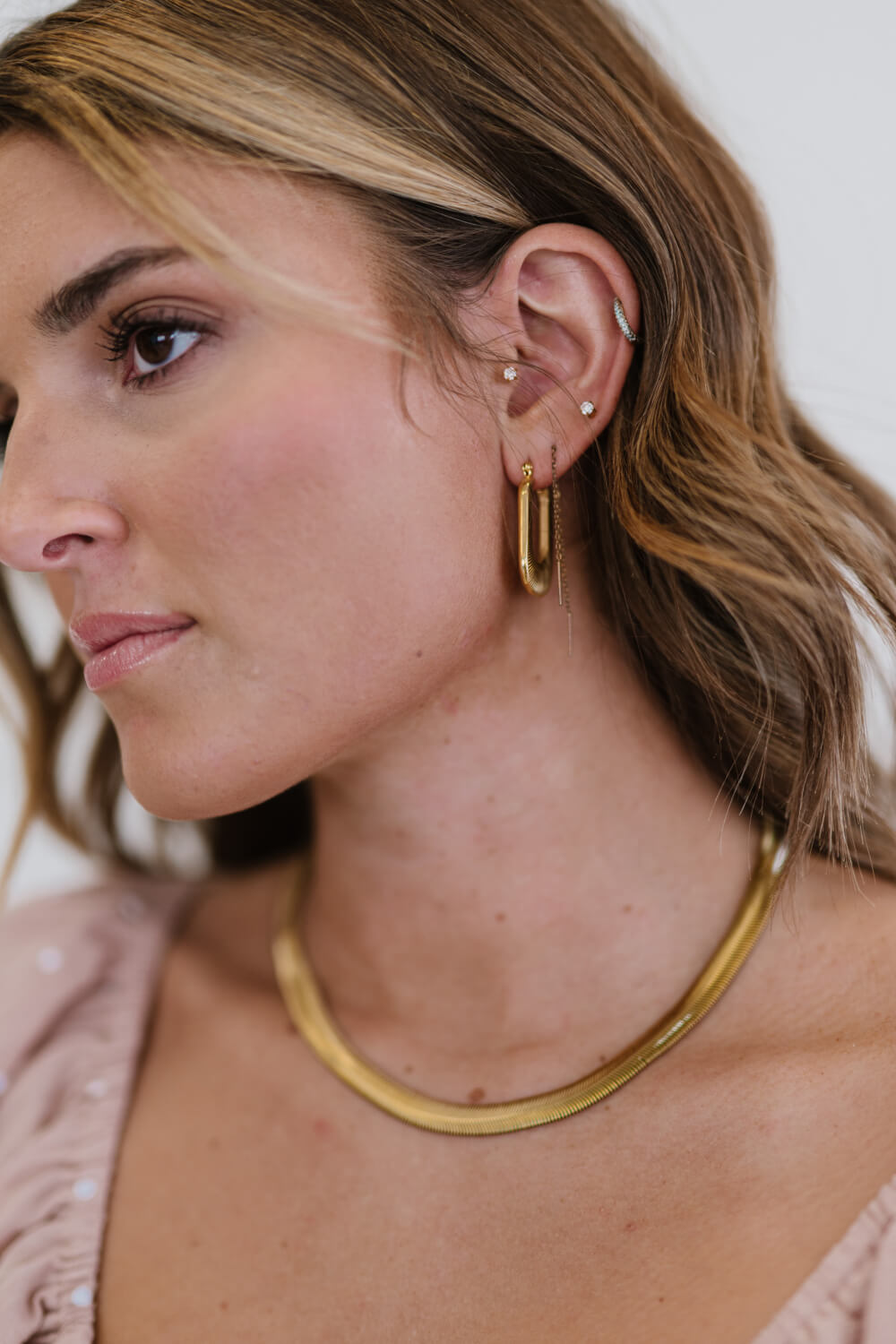 Gold textured rectangular hoop earrings with a delicate chain detail.
