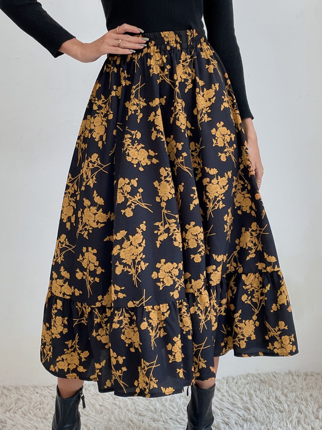 Tiered midi skirt in black with a yellow floral print and ruffled hem.