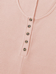 Blush pink waffle knit button-down romper with henley neckline and tortoise buttons.