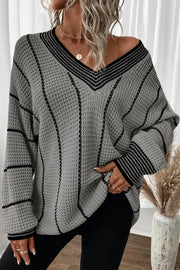 Gray knit oversized V-neck sweater with black vertical stripes and striped cuffs.