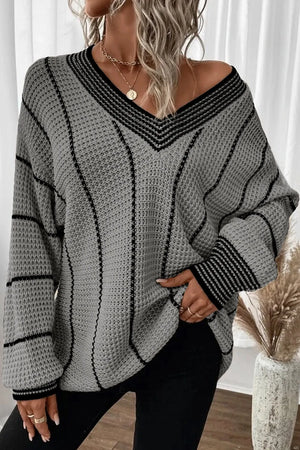 Gray knit oversized V-neck sweater with black vertical stripes and striped cuffs.