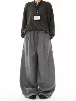 Men's gray wide-leg drawstring sweatpants with a relaxed fit and visible stitching details.