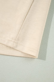 Cream ruffled shoulder sweatshirt detail showing ribbed cuffs and stitching.