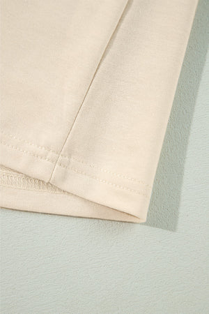 Cream ruffled shoulder sweatshirt detail showing ribbed cuffs and stitching.