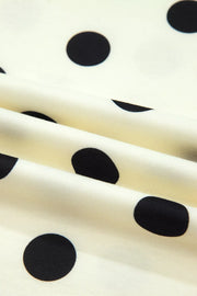 Polyester t-shirt with black polka dots on a cream background, showing fabric texture.