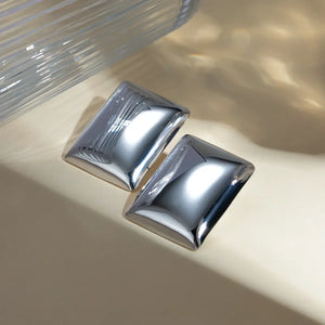 Sculpted silver rectangle earrings with a polished finish and subtle ridged detail.