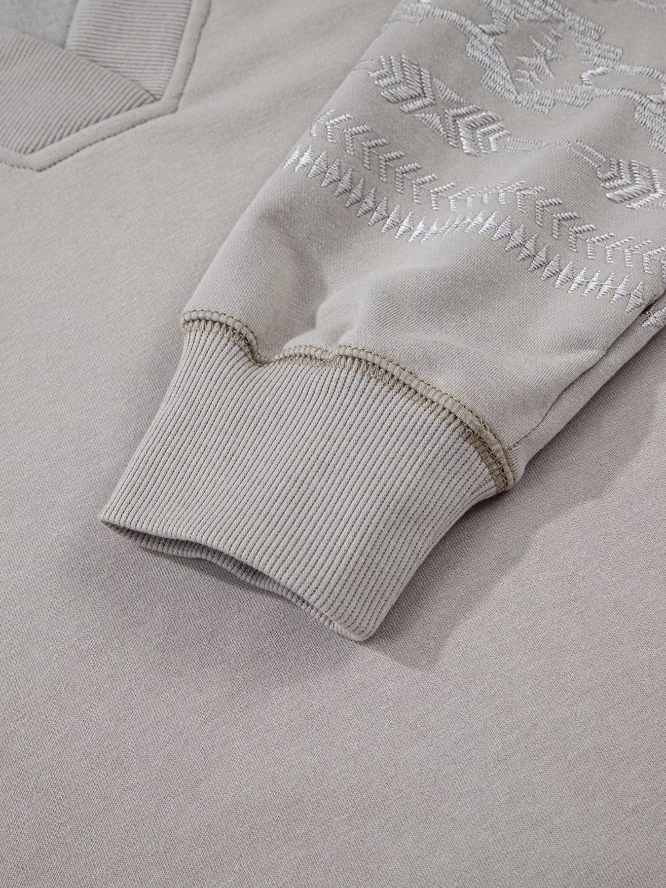 Gray V-neck sweatshirt with Aztec embroidery on the sleeve and ribbed cuffs.