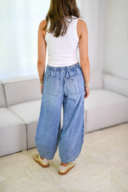 Light wash denim balloon-leg jeans with drawstring waist and back pockets.