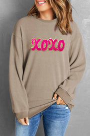 Tan ribbed sweatshirt with pink XOXO appliqué detail