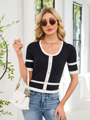 Black cropped knit sweater with white trim and decorative buttons.