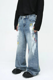 Painterly wash wide-leg denim trousers in medium blue with artistic paint splatters and wide leg.
