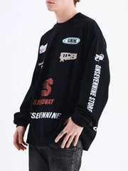 Black cotton long sleeve t-shirt with multiple graphic patches and text details.