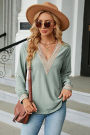 Sage green textured V-neck blouse with lace trim on neckline and cuffs.