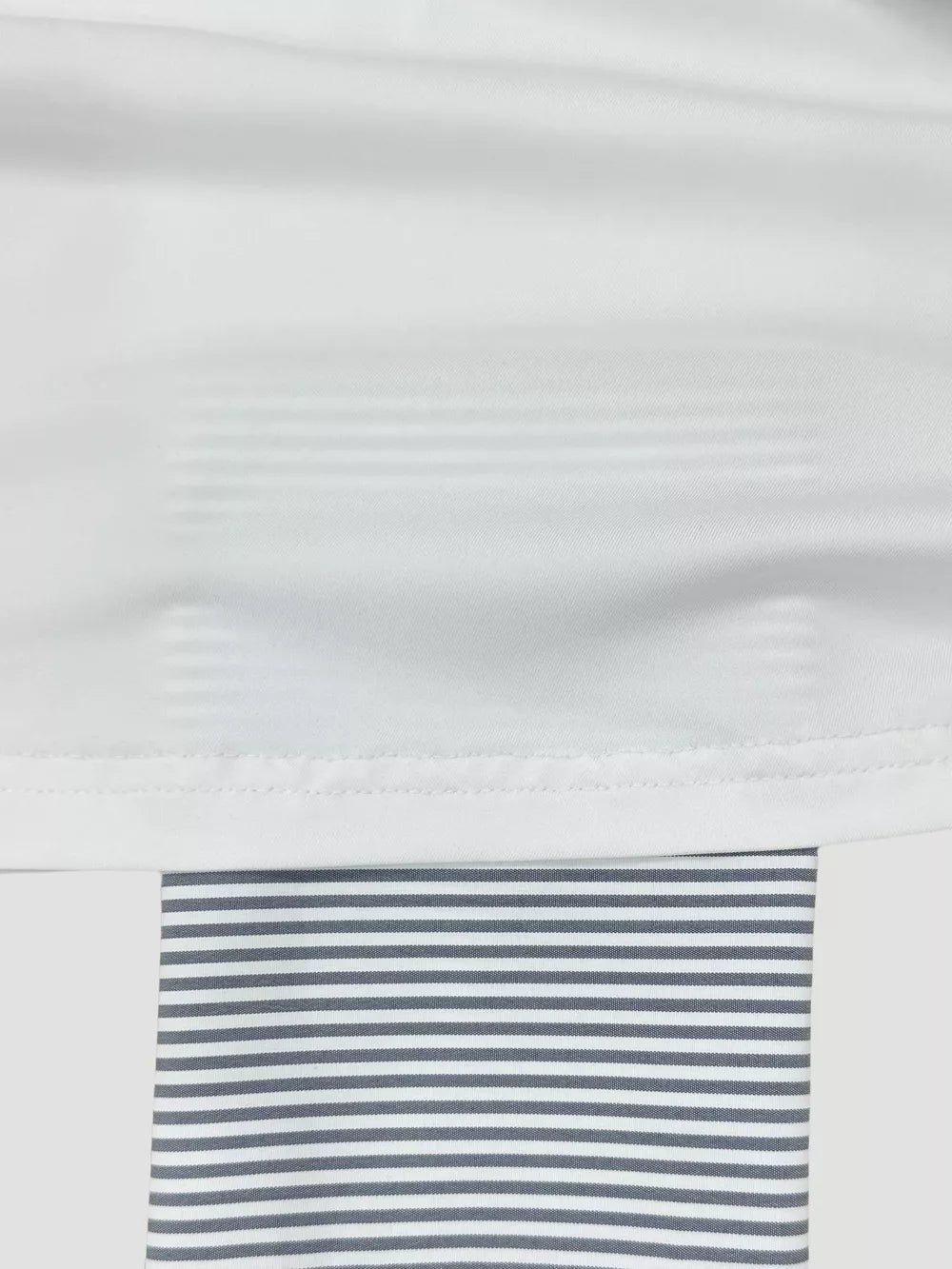 White asymmetrical one-shoulder camisole with subtle tonal stripes and grey striped trim.