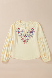 Pastel yellow blouse with embroidered floral detail and poet sleeves.