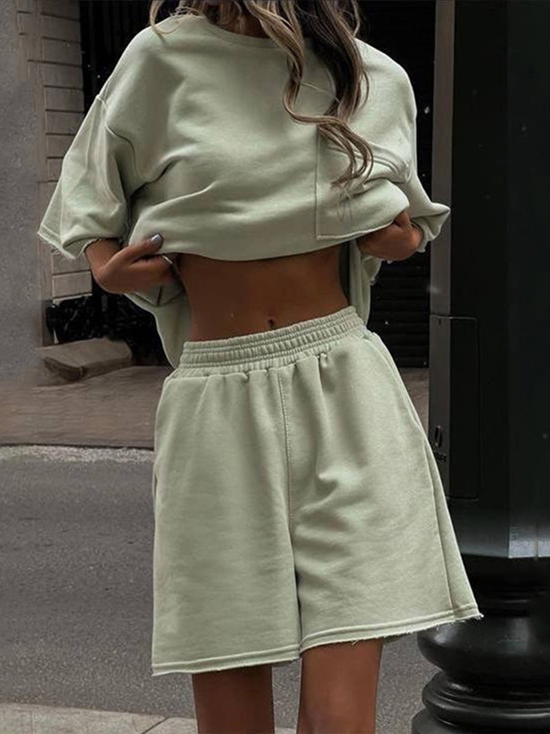 Sage raw-edge pocket tee and Bermuda shorts set with elastic waistband.