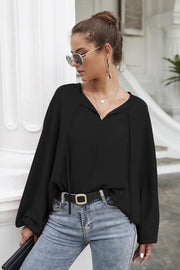 Black voluminous sleeve blouse with keyhole neckline and tie detail.