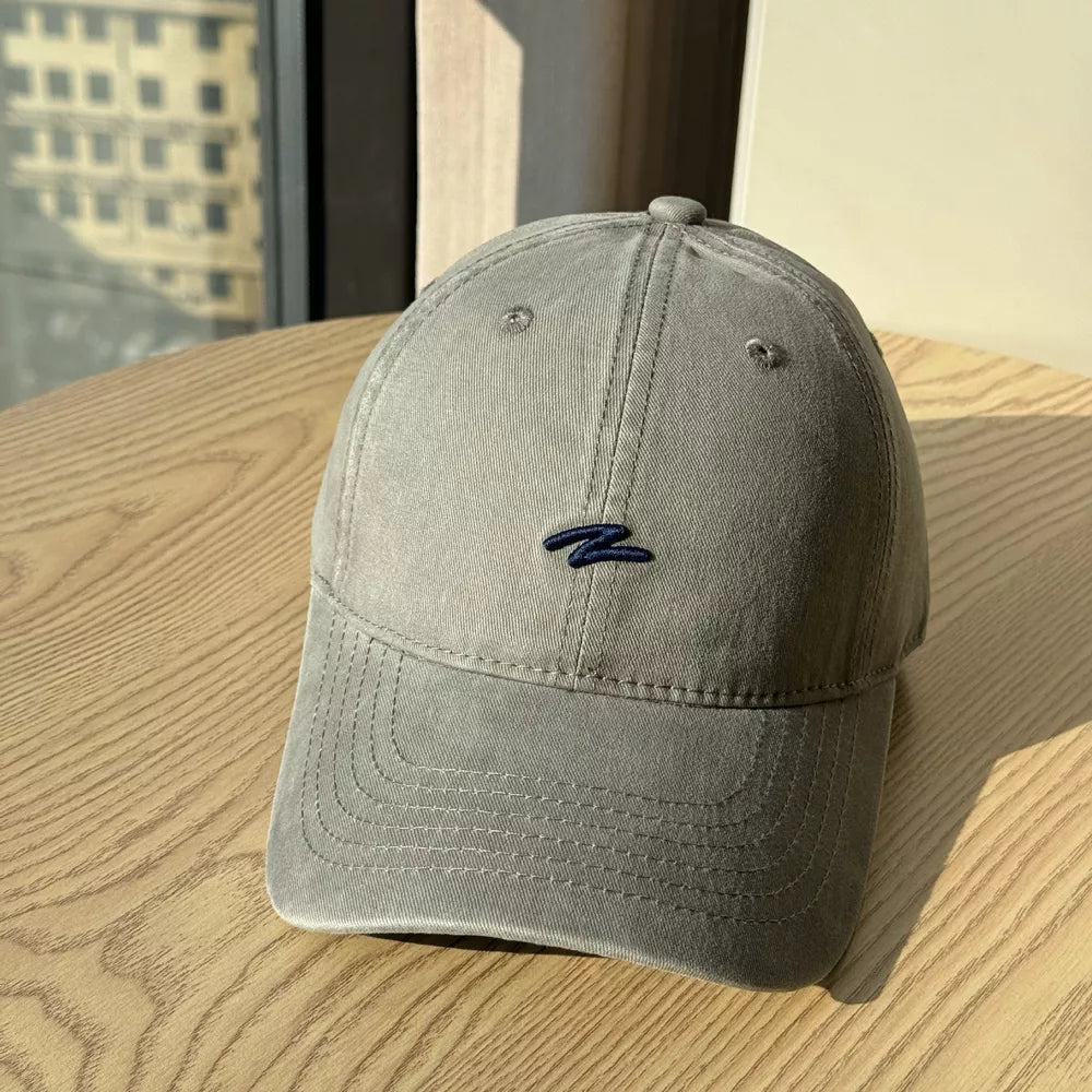 Distressed vintage cotton baseball hat in dark gray with embroidered detail and curved brim.