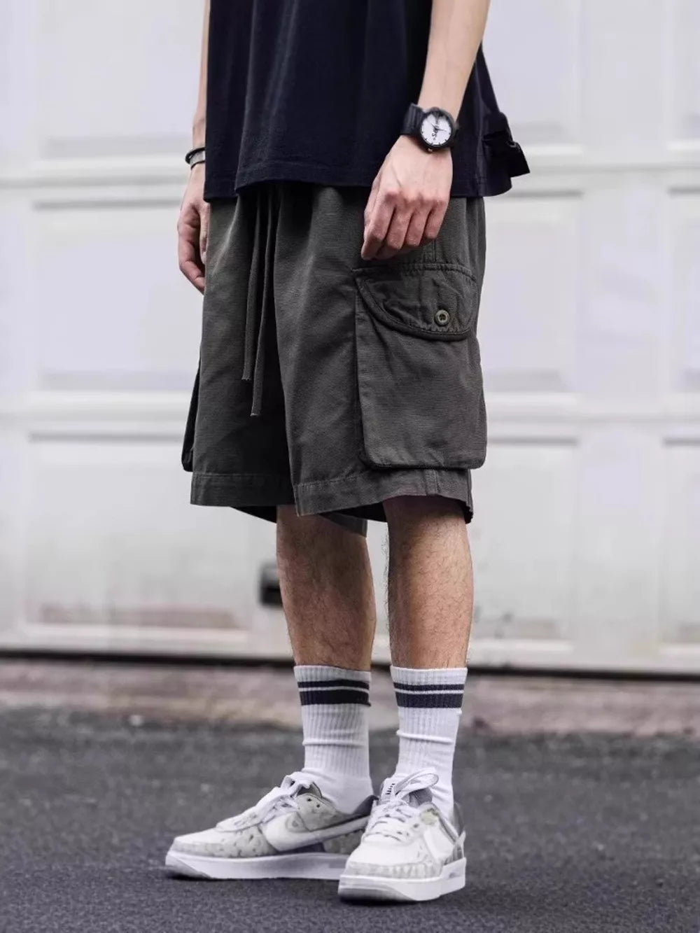 Army green cargo shorts with drawstring waist and button flap pocket.