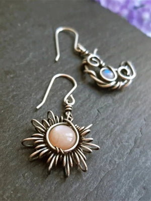 Celestial mismatched drop earrings in silver wirework with sun and moon designs.