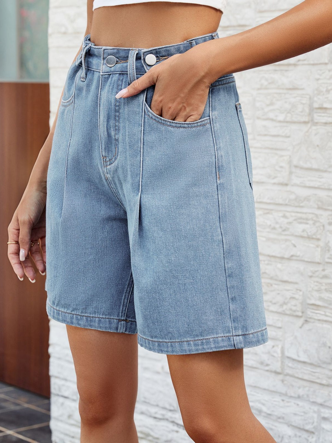 Pleated denim bermuda shorts in light wash with button closure and front pockets.