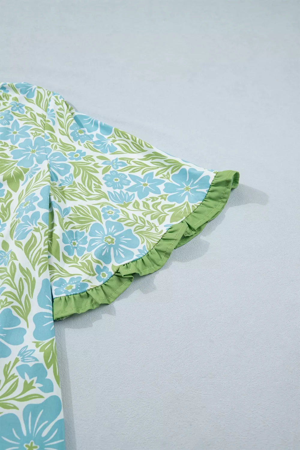 Mini dress with blue floral print and green ruffle trim on sleeve.