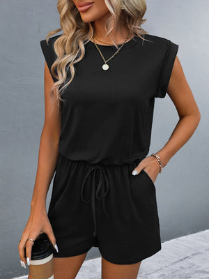 Black shoulder pad romper with drawstring waist and cuffed sleeves.