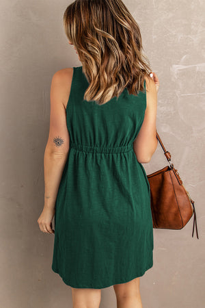Green button-down mini dress with gathered waistline and sleeveless cut.