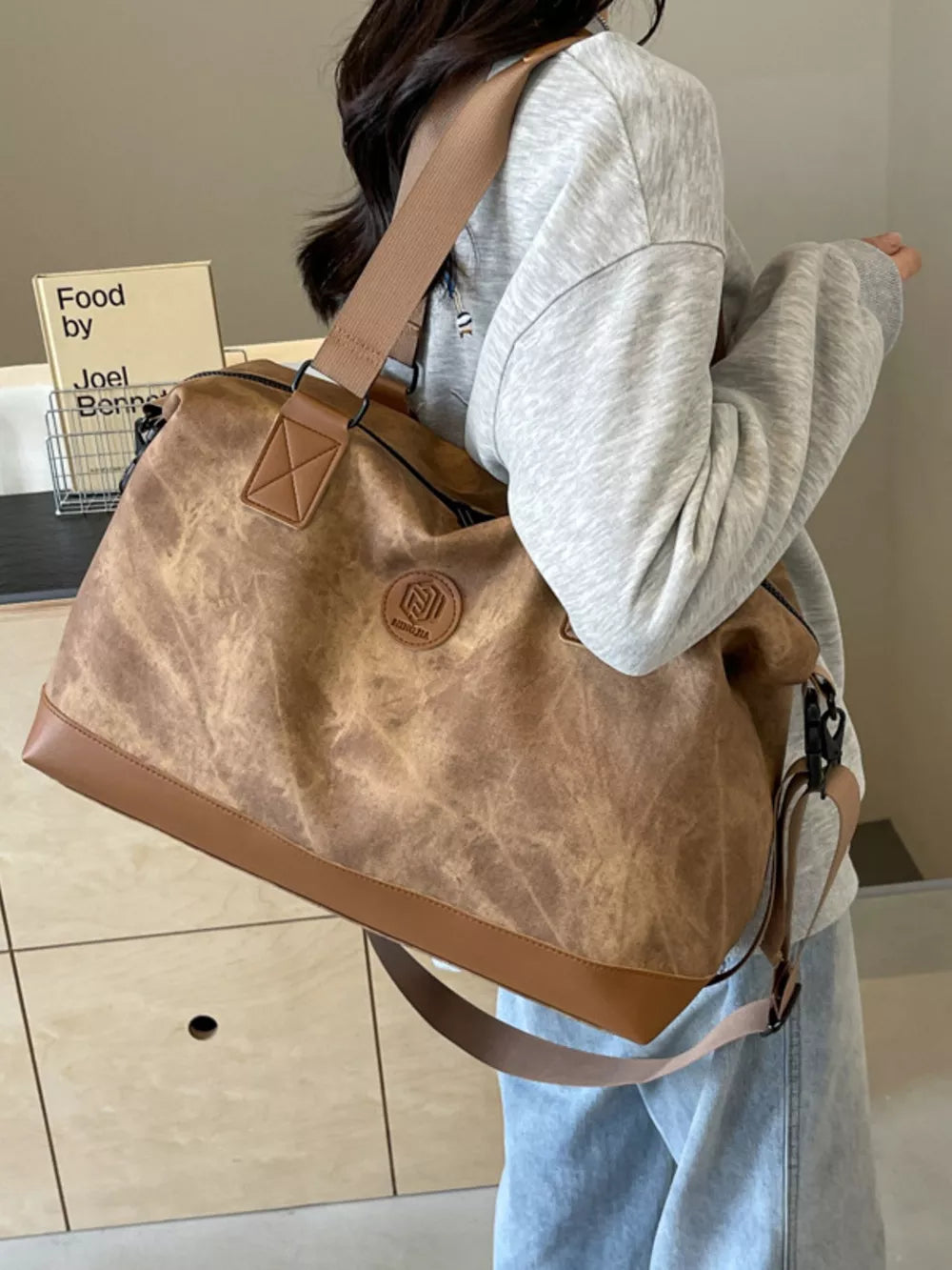 Distressed brown duffle bag with adjustable strap and faux leather trim