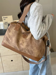 Distressed brown duffle bag with adjustable strap and faux leather trim