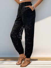 Black textured lace jogger trousers with elastic waistband and pockets.