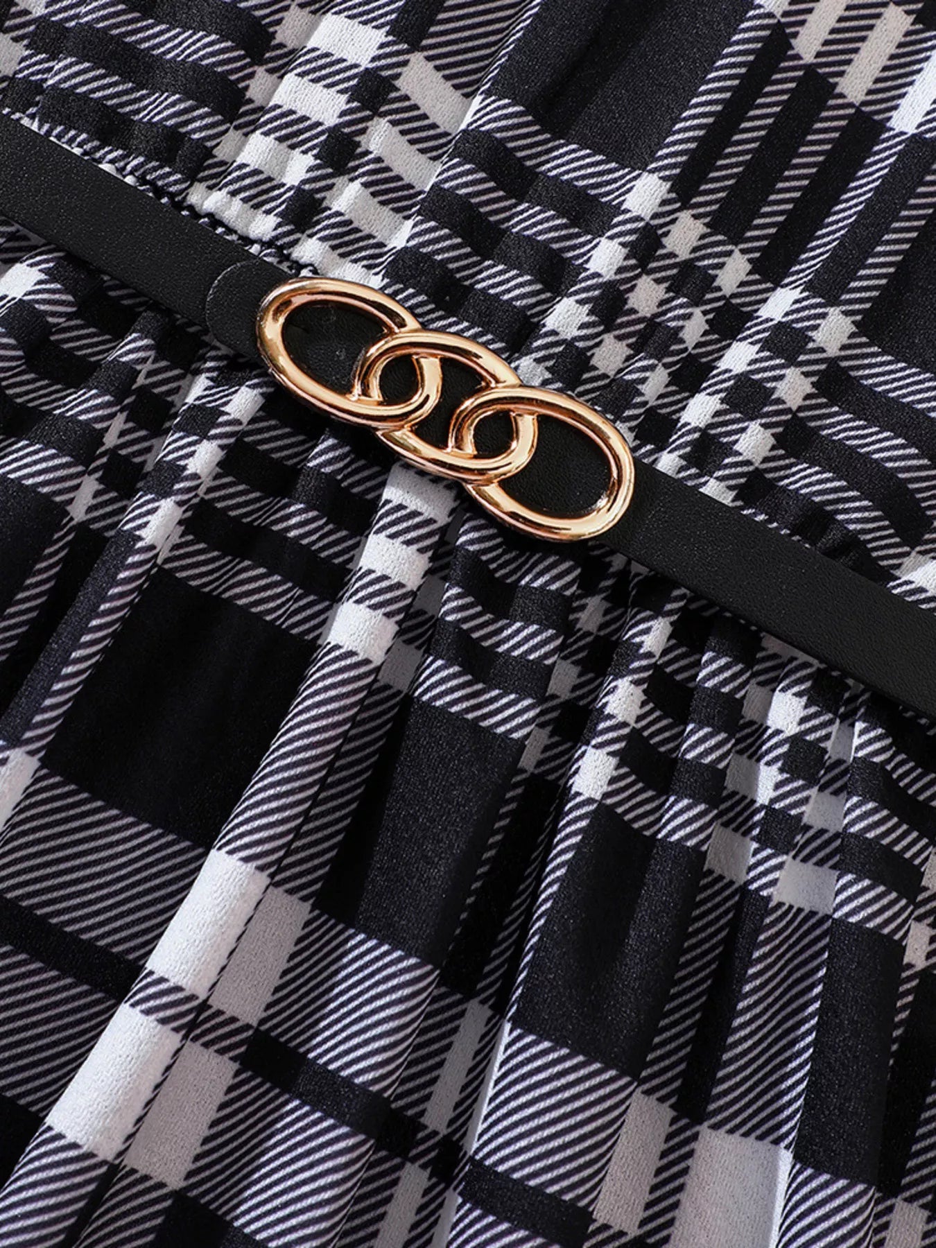 Belted plaid dress in black and white with gold chain detail.
