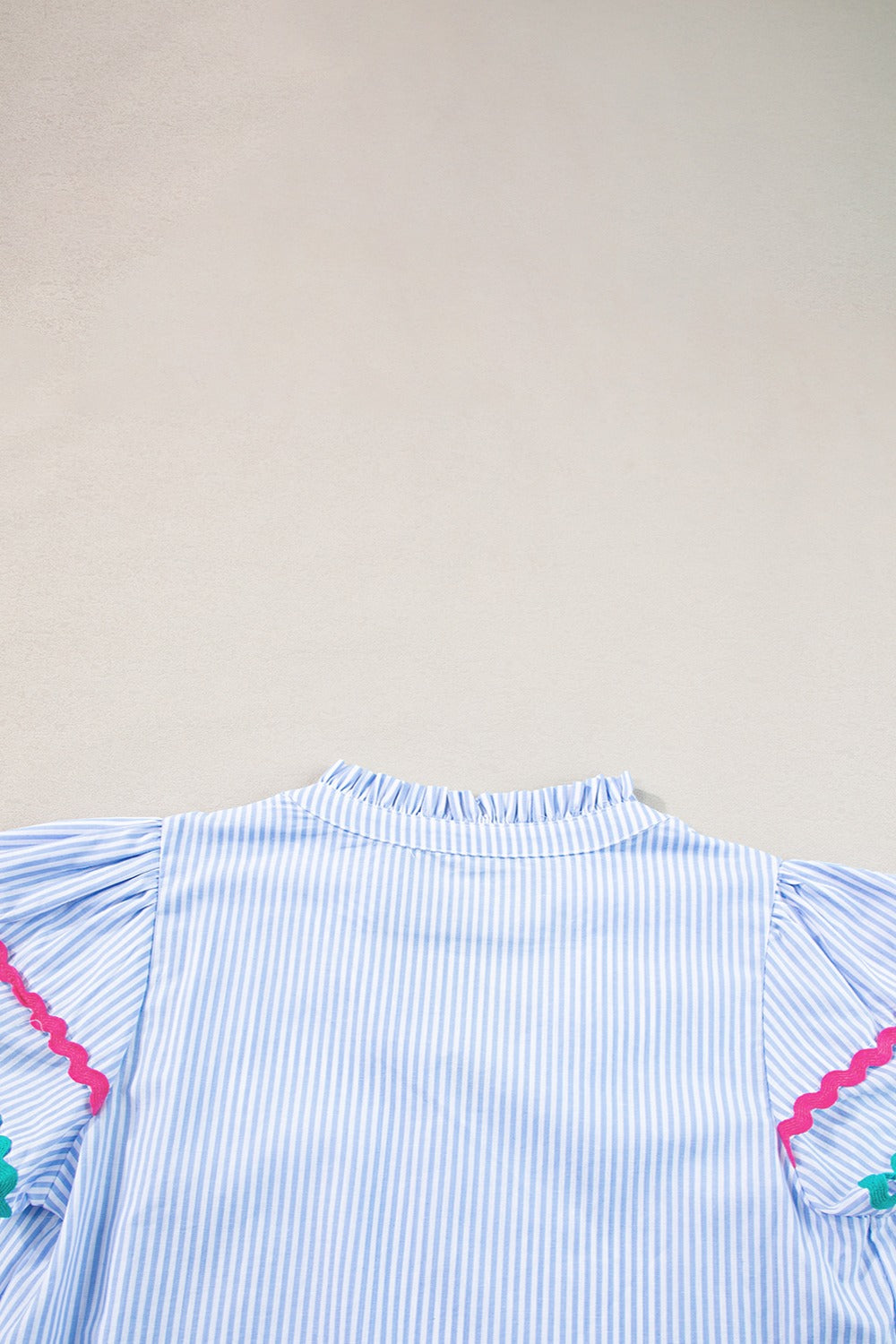 Light blue and white striped blouse with ruffled neckline and scalloped trim sleeves.