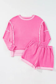 Fuchsia pink cotton loungewear set with contrast trim on crewneck sweatshirt and shorts.