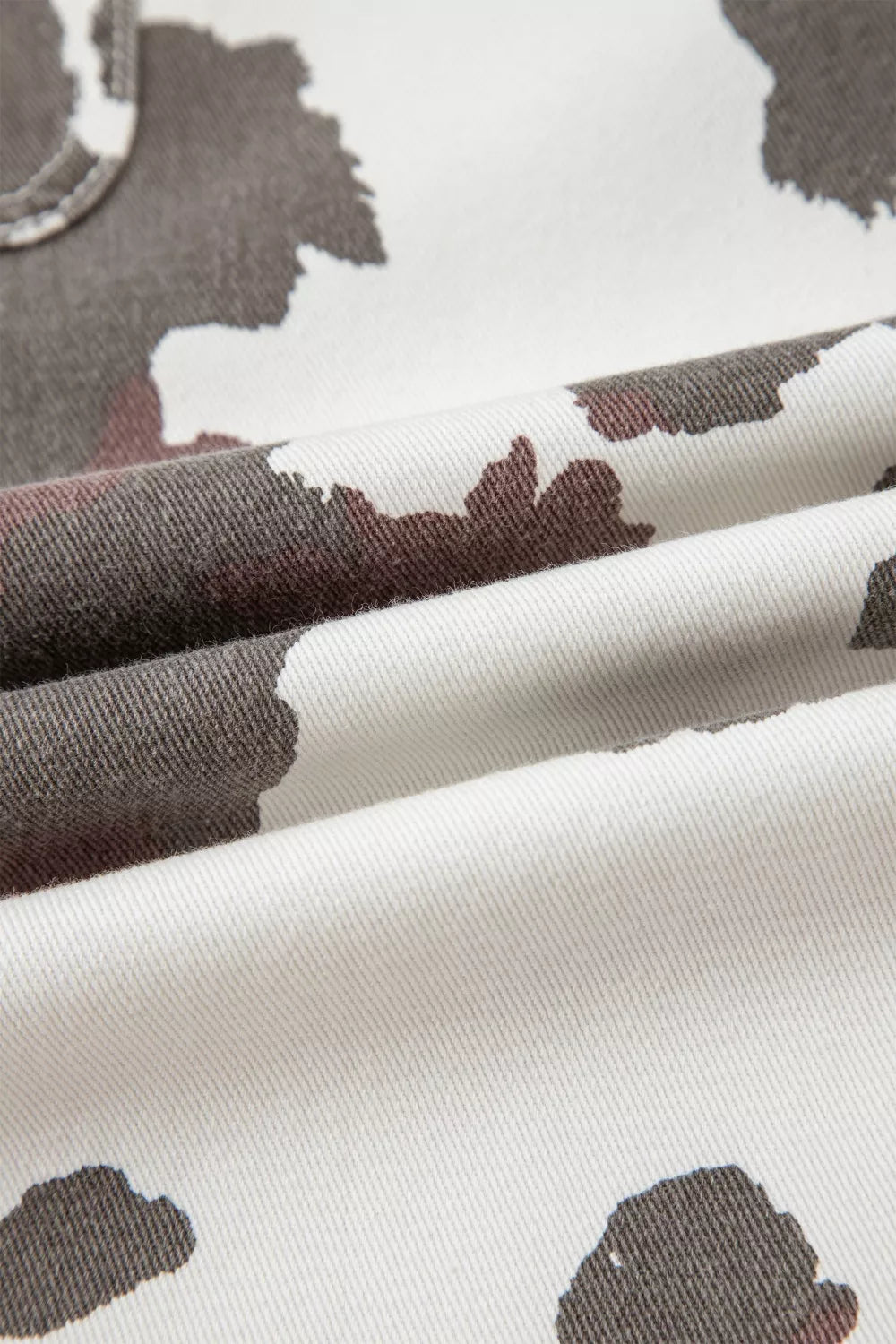 Cow print denim jeans with utility pockets, white with brown and grey abstract cow spots.
