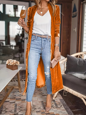Tangerine velvet duster coat with fluid silhouette, open front, long sleeves, worn with jeans.