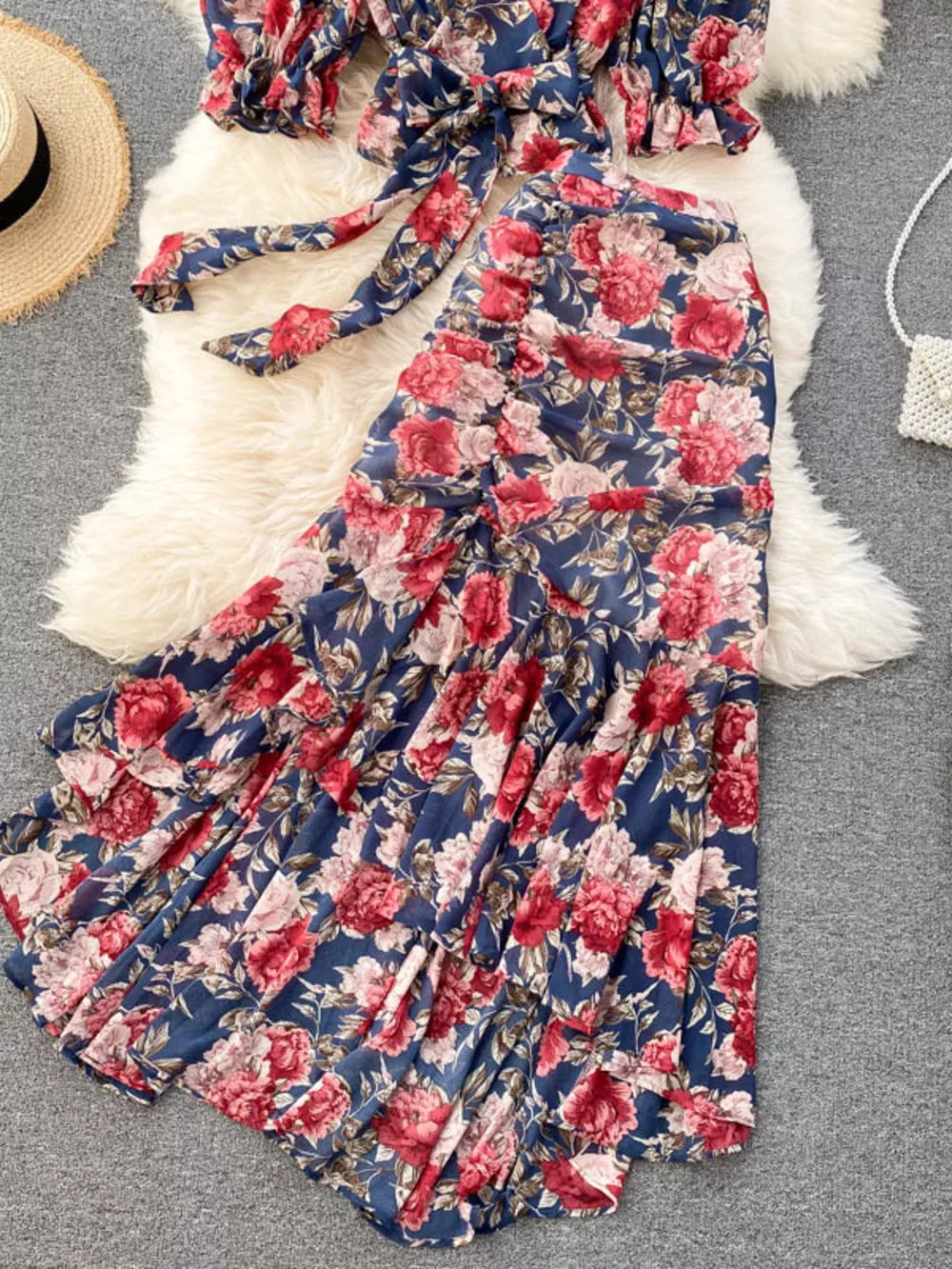 Chic floral two-piece crop set in dark blue with red and pink flowers, featuring a tie-front top and tiered ruffled skirt.
