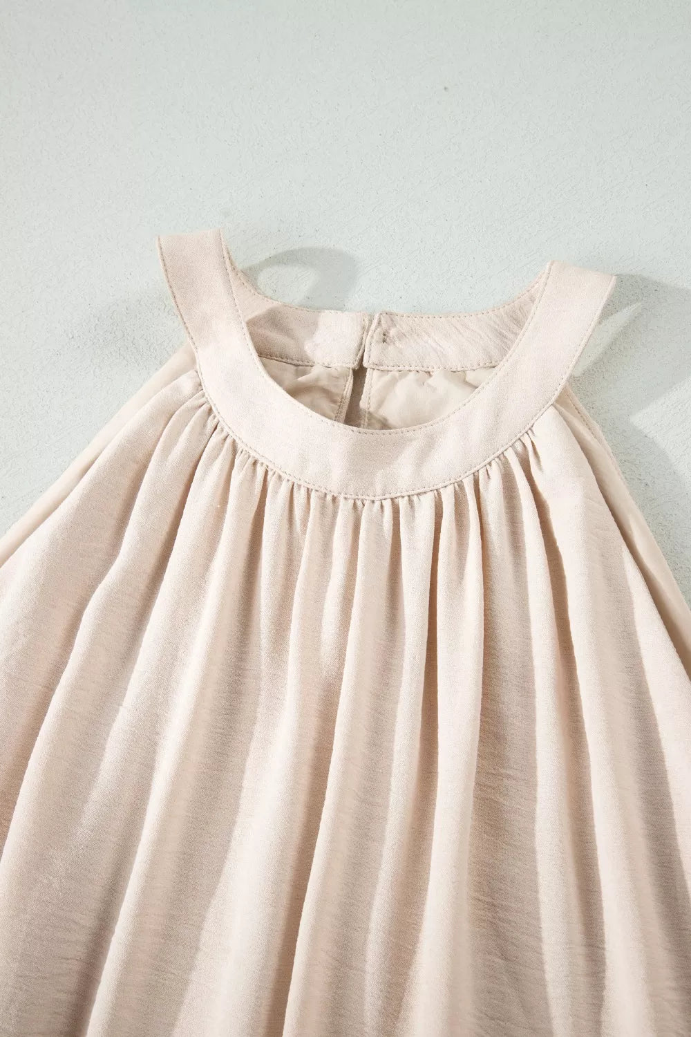 Beige halter maxi dress with gathered neckline and airy fabric.