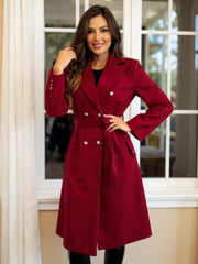 Red tailored double-breasted trench coat with waist tie and button details.